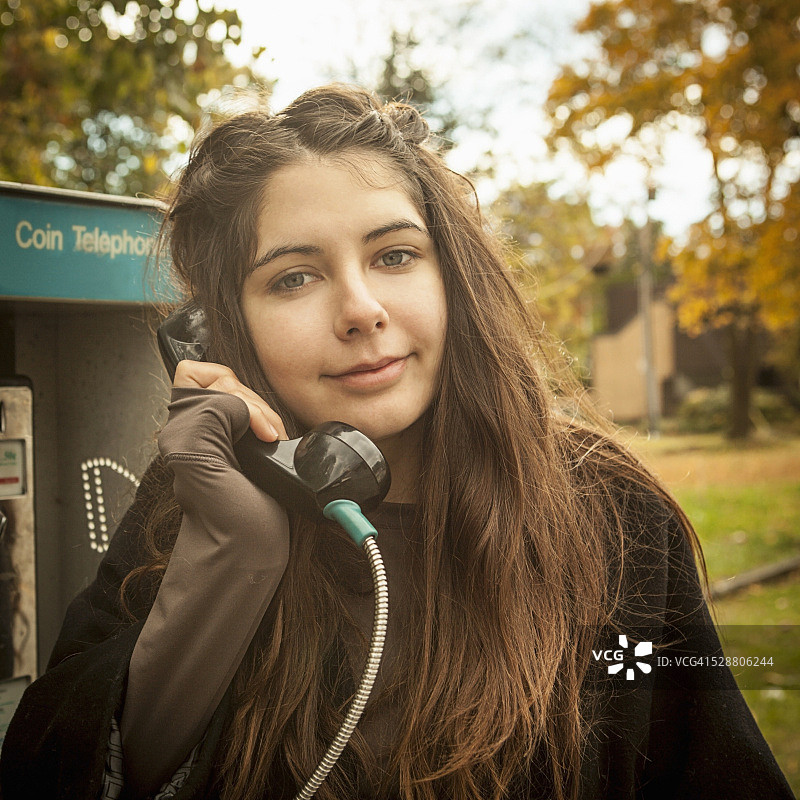 一个年轻的成年妇女在公用电话上说话的肖像图片素材