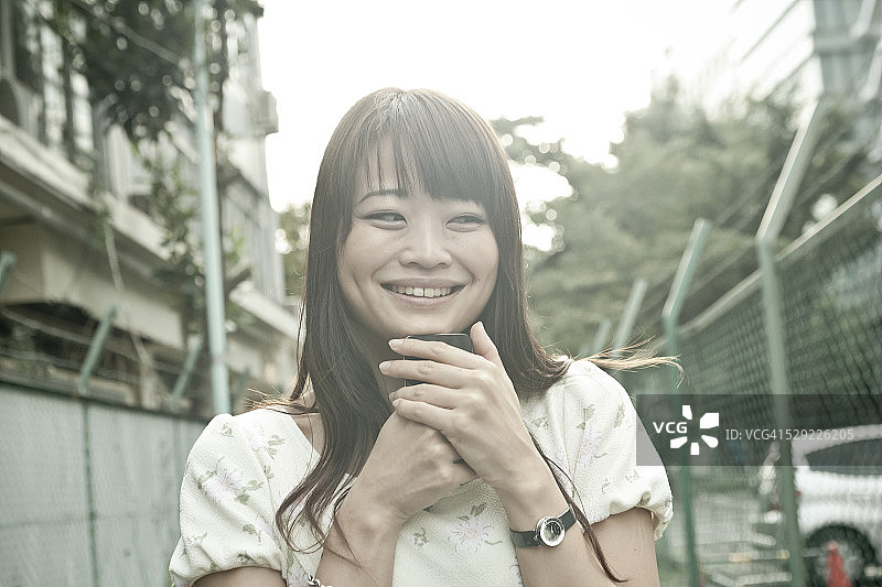 一个日本女人拿着手机，微笑着图片素材