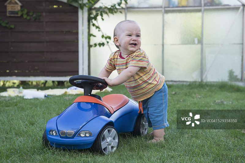 德国巴伐利亚慕尼黑，一个小男孩和他的玩具车在草坪上哭泣图片素材
