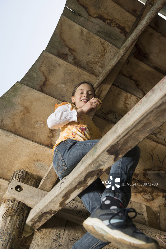 德国巴伐利亚慕尼黑，一个女孩坐在树屋的木条上吃松饼图片素材