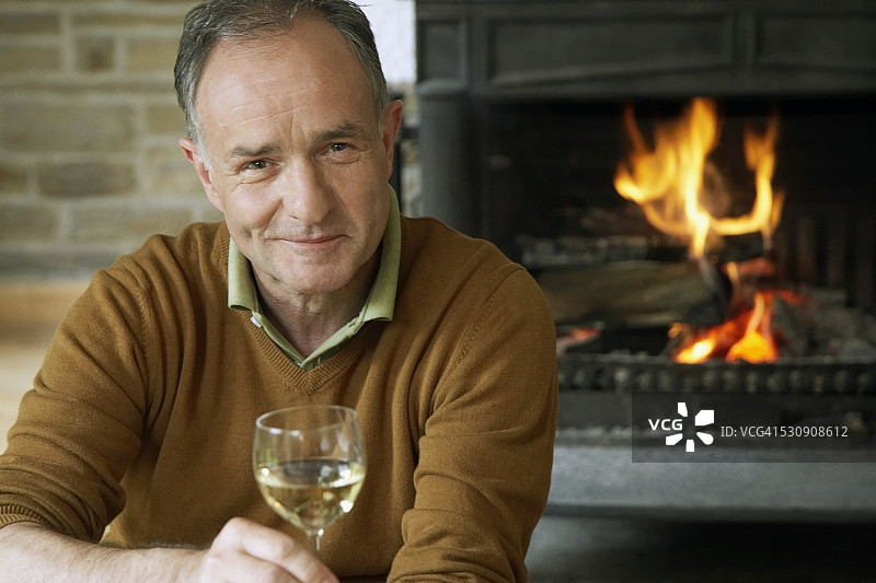 男人坐在壁炉旁，喝着酒图片素材