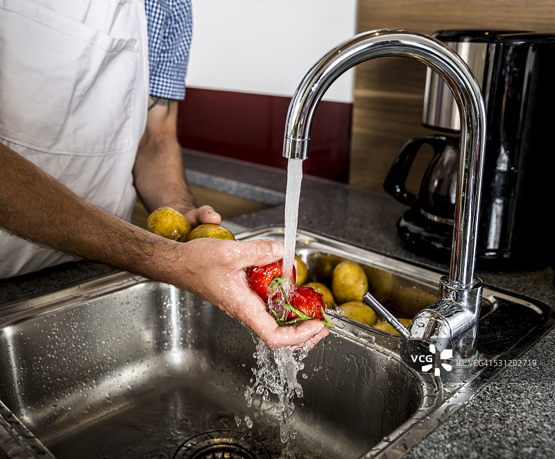 奥地利，男人在厨房洗蔬菜图片素材