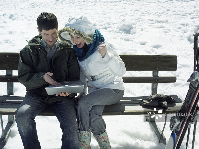一对夫妇在滑雪坡上使用笔记本电脑图片素材