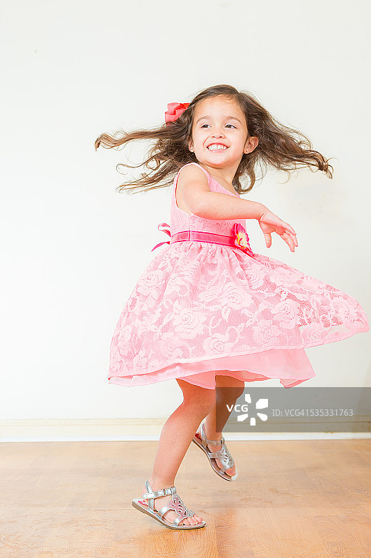 可爱的女孩穿着粉红色的裙子旋转图片素材