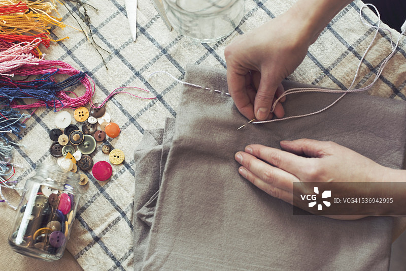 高角度的妇女缝纫织物在家里的桌子上图片素材