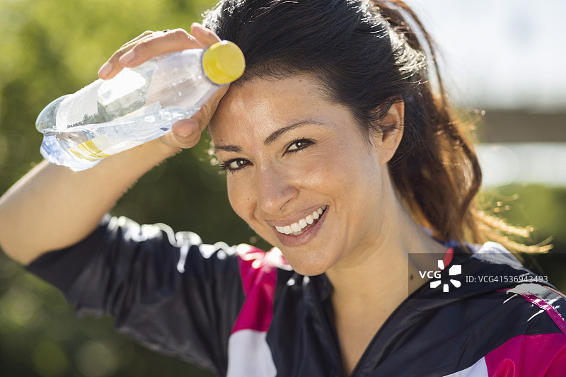 快乐健康的女人拿着水瓶擦汗的肖像图片素材