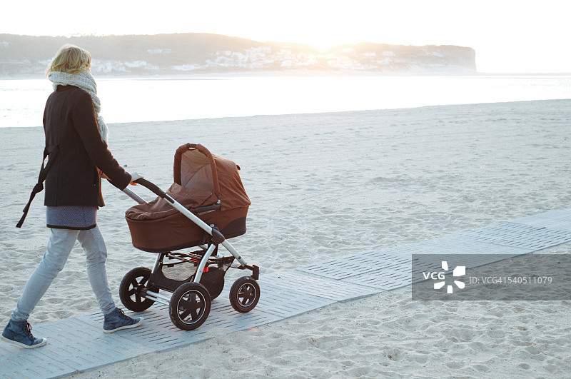 妈妈推着婴儿车在海滩上散步图片素材