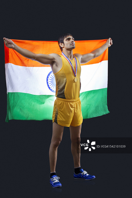 全身的男性奖牌得主与印度国旗在黑色的背景向上看图片素材