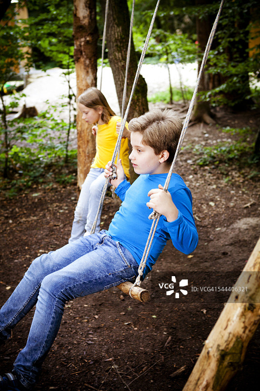 德国巴伐利亚州慕尼黑，孩子们在森林营地玩秋千图片素材