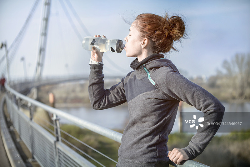 年轻女子慢跑后用瓶子喝水图片素材
