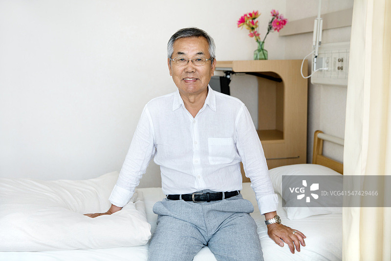日本老人坐在医院病床上的肖像图片素材