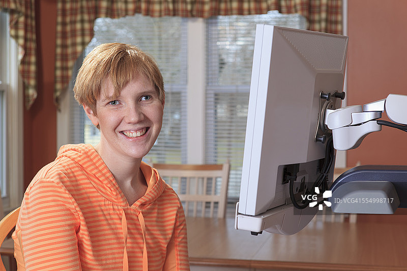 一个有视觉障碍的年轻女性坐在她的桌面放大镜前的肖像图片素材
