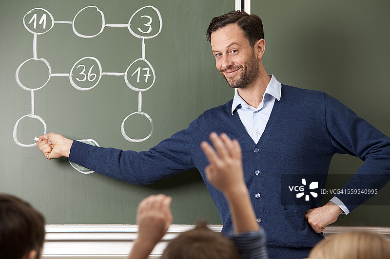 微笑的老师在黑板上做算术题图片素材