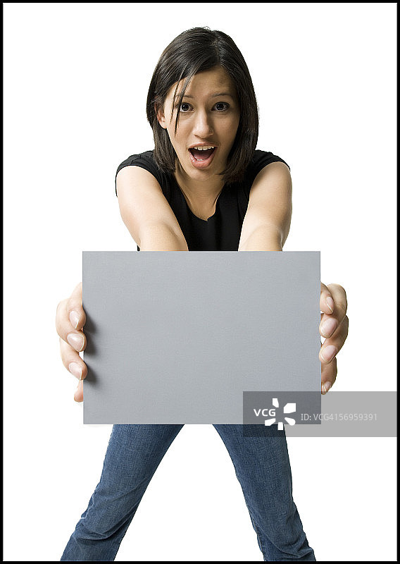 一个年轻女子举着空白牌子的肖像图片素材