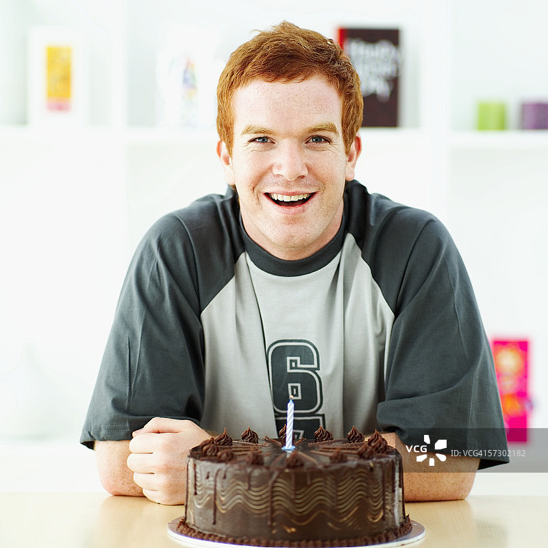 一个年轻人坐在一个生日蛋糕的肖像图片素材
