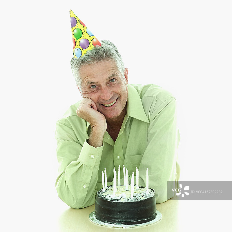 一个老人坐在生日蛋糕后面的肖像图片素材