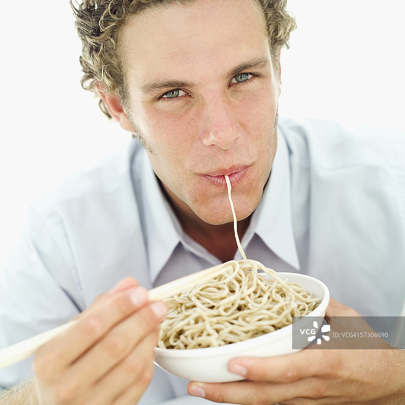 一个男人用筷子吃面条的肖像图片素材