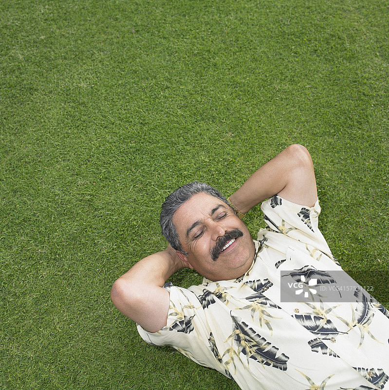 成熟的男人在绿色的草坪上休息图片素材
