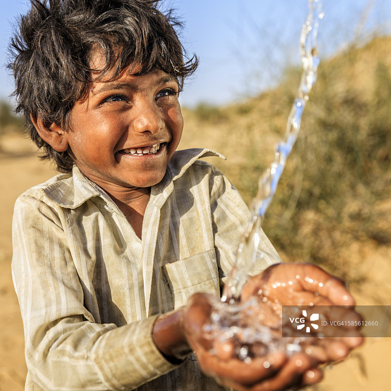 印度拉贾斯坦邦沙漠村庄的一个小男孩喝着淡水图片素材