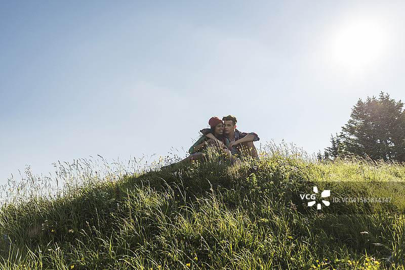 奥地利，蒂罗尔，坦海默·塔尔，一对年轻情侣在高山草地上拥抱图片素材