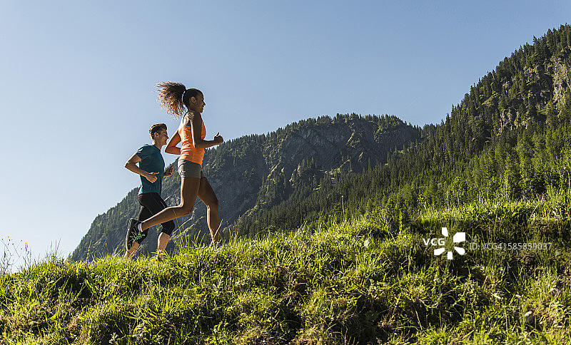 奥地利，蒂罗尔，坦尼姆山谷，年轻夫妇在高山风景中慢跑图片素材