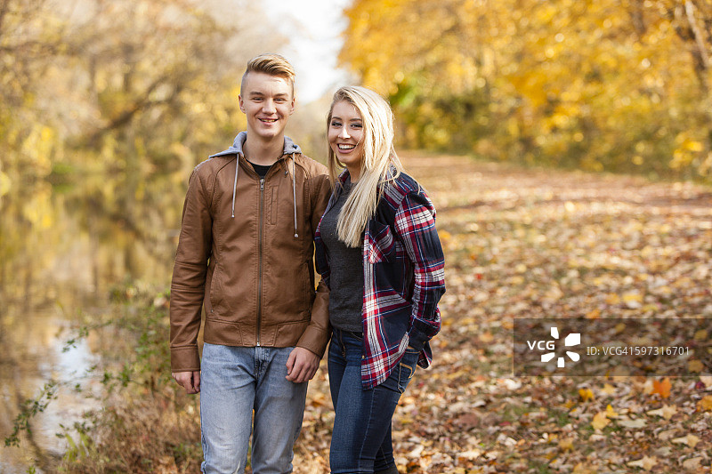 一个十几岁的男孩和一个成年的姐姐在秋天的森林里图片素材