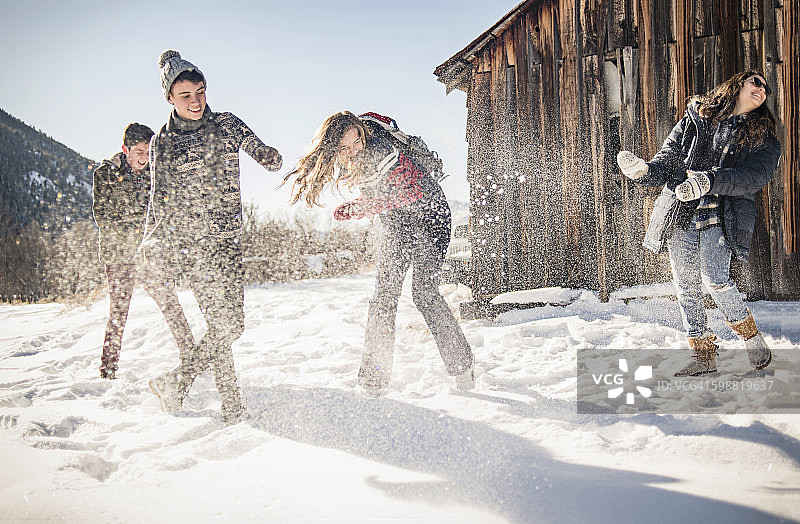 朋友们在冬天的小屋外面玩雪图片素材