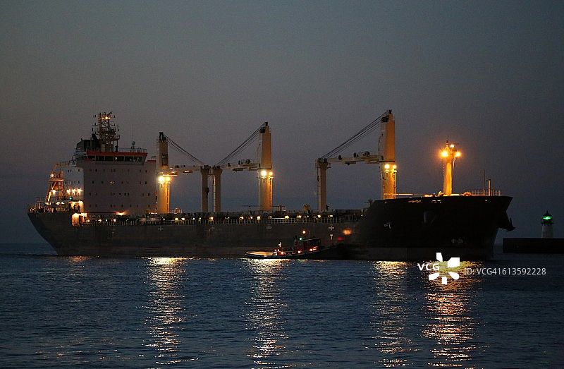 港口拖船在夜间协助一艘货船图片素材