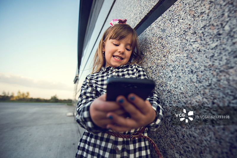 微笑的商务女孩在户外用智能手机发短信。图片素材