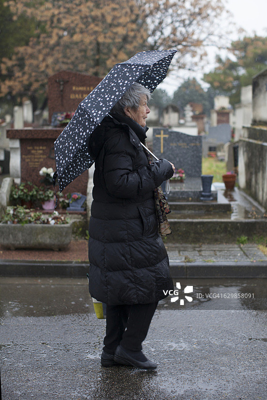 在墓地里打着伞的老妇人图片素材