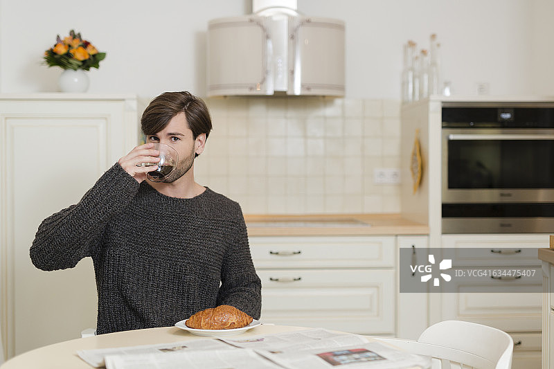 一个男人坐在厨房的早餐桌旁喝着咖啡图片素材