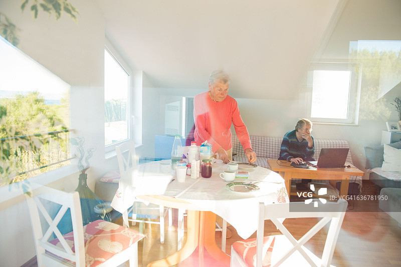 克罗地亚布拉克，穿粉红色衣服的年长白种妇女正在准备早餐图片素材