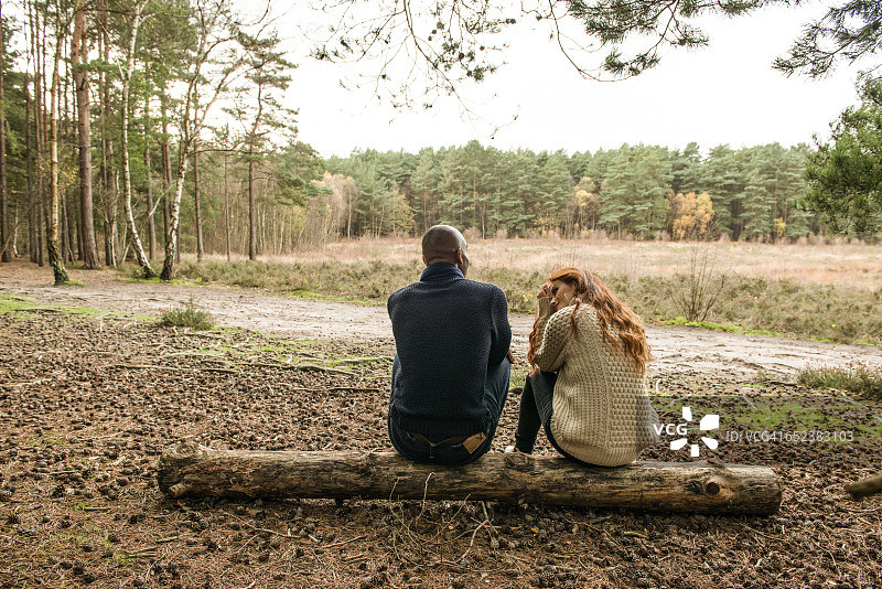 一对年轻夫妇在秋天的森林散步，与大自然交流图片素材
