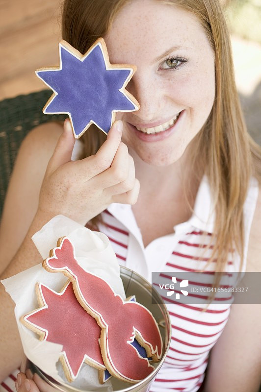 一个女人拿着一块星形饼干放在眼前(美国7月4日)图片素材