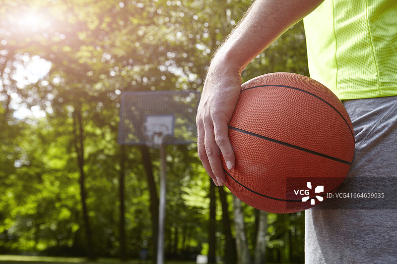 一个年轻的男篮球运动员抱着球的特写镜头图片素材
