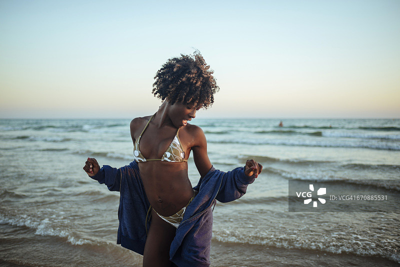 日落时分，快乐的年轻女子在海边跳舞图片素材