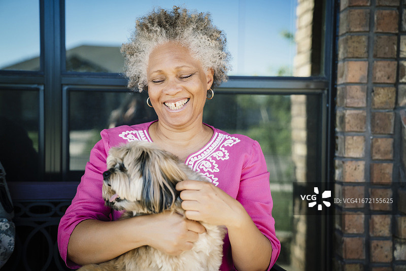 一个黑人妇女在窗口附近抱着一只狗图片素材