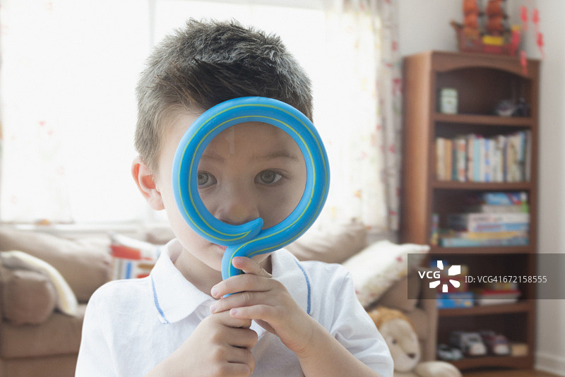 混血儿男孩拿着玩具放大镜在面前图片素材
