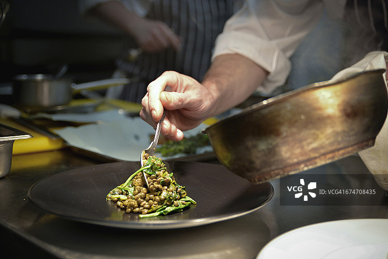 厨师用勺子舀扁豆放到盘子上图片素材