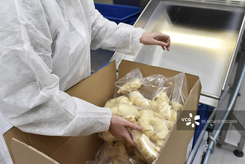 在烘焙工厂包装牛角面包的工人图片素材