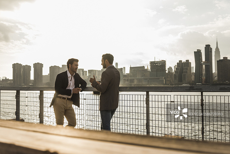 美国，纽约市，两个商人在东河交谈图片素材