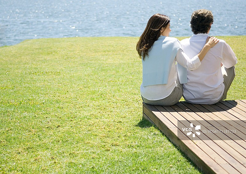 一对成熟的夫妇坐在靠近水的木栈道尽头图片素材