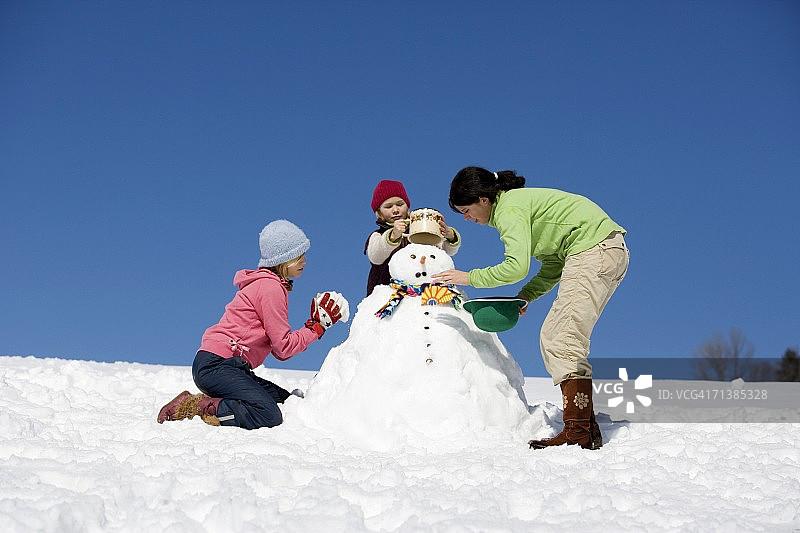 奥地利，女孩(6-17岁)堆雪人，低角度拍摄图片素材