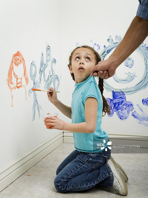一个男人拉一个女孩的顶部，而绘画在墙上的特写图片素材