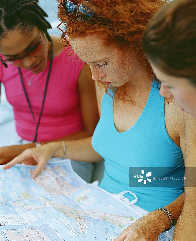 三个年轻女人的特写，坐着看地图，百慕大图片素材