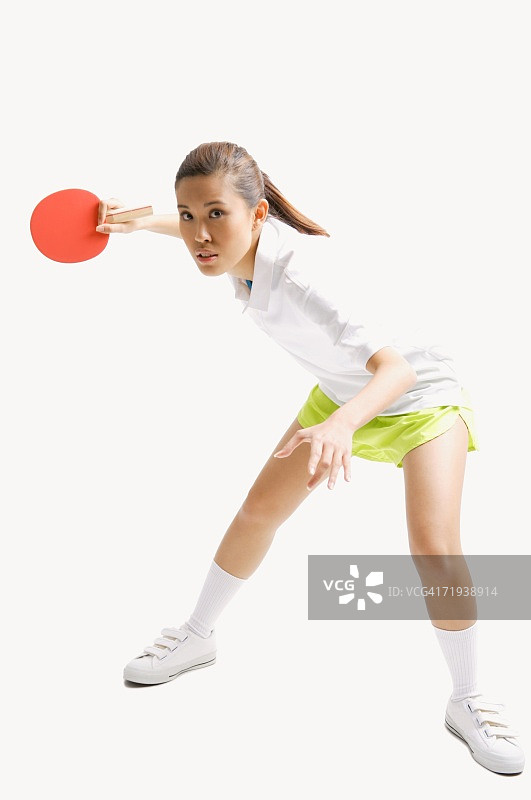 年轻女子在打乒乓球，摄影棚里拍摄图片素材