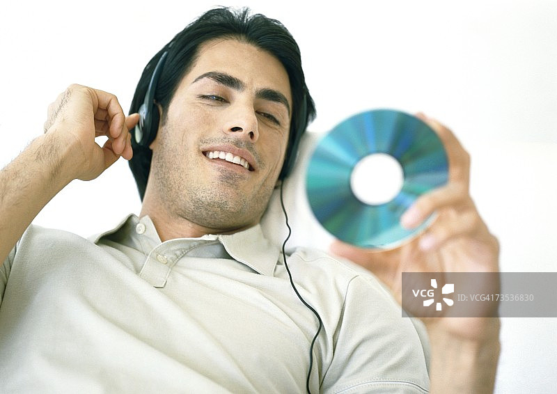 男人听着耳机，看着CD图片素材