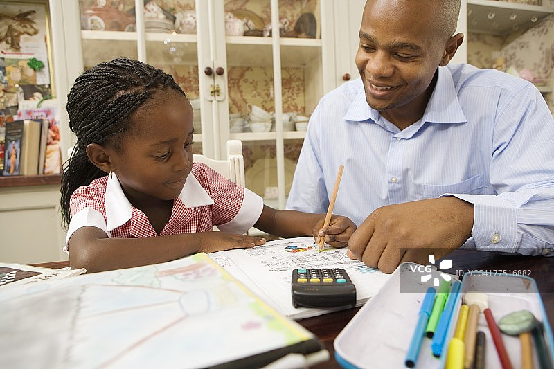 非洲男人帮助他的女儿做家庭作业图片素材