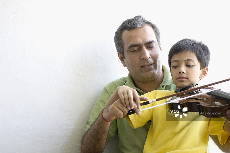 一个中年人在教儿子拉小提琴图片素材