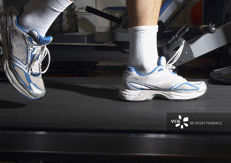 男人的脚在健身房里的跑步机上图片素材